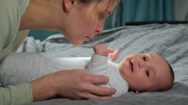 Anne yeni doğan oğlunu gıdıklıyor, çocuğu sesli güldürüyor.