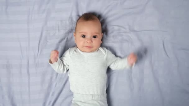 Infant lies still on blanket looking attentively into camera — Stock Video