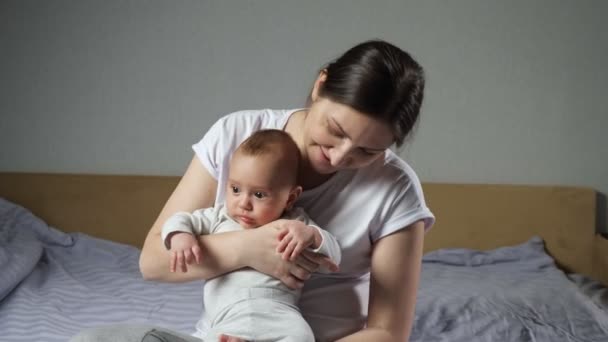 Brunett mor smeker söt nyfödd pojke sitter på sängen — Stockvideo