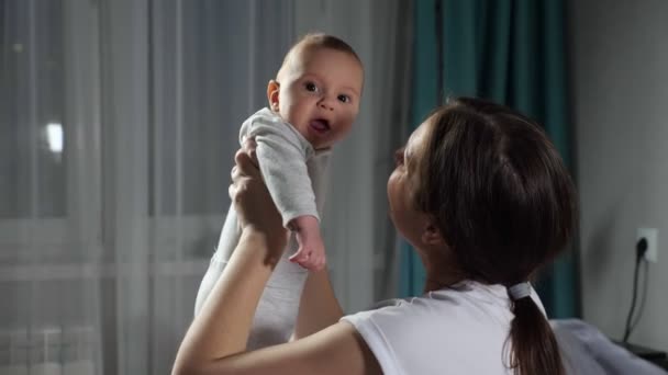 Jong brunette moeder strelt baby jongen zitten in slaapkamer — Stockvideo