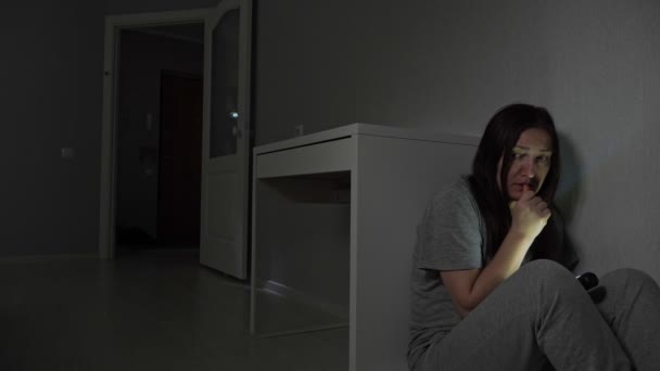 Mujer joven se esconde detrás del escritorio de ladrón con linterna — Vídeo de stock
