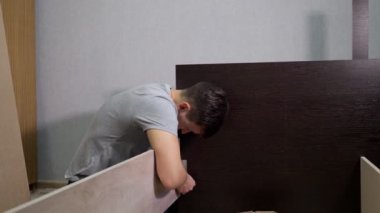 Genç adam yatağı tornavidayla birleştiriyor.