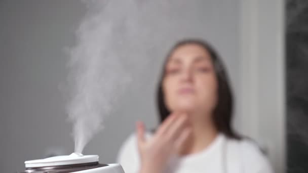 Mujer aplica crema hidratante en la cara cerca del humidificador — Vídeos de Stock
