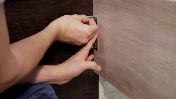 Unrecognizable male furniture assembler staples corners with a metal plate using a screwdriver — Stock Video