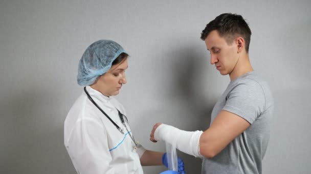 Brunette médecin examine l'avant-bras cassé du jeune homme — Video