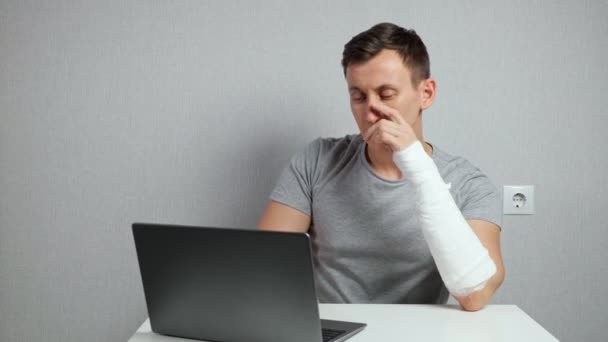 Brunet man works distantly feeling pain in broken forearm — Stock Video