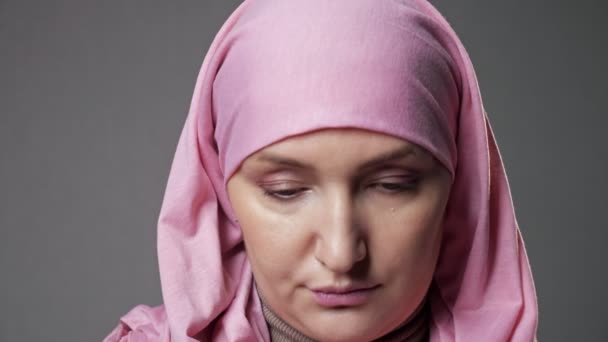 Мусульманка поднимает голову и улыбается, глядя в камеру — стоковое видео