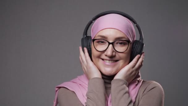 Молода жінка в хіджабі слухає музику через навушники — стокове відео