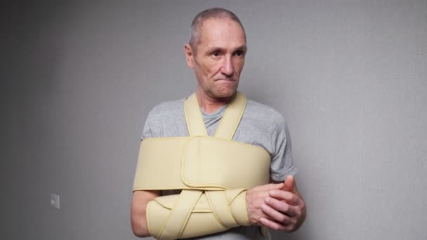 Hombre mayor con vendaje fijo comprueba los dedos y las articulaciones — Vídeo de stock