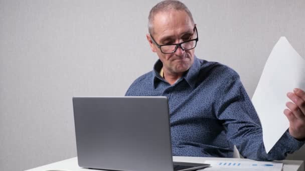 Hombre mayor se sienta cerca de informes de verificación de computadoras en la oficina — Vídeos de Stock
