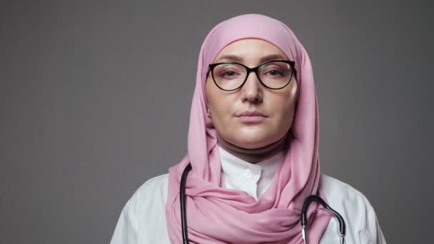 Девушка-доктор в хиджабе широко улыбается, глядя в камеру. — стоковое видео