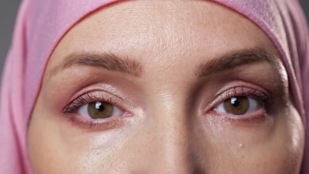 Молода жінка в рожевому хіджабі блимає, дивлячись в об'єктив камери — стокове відео