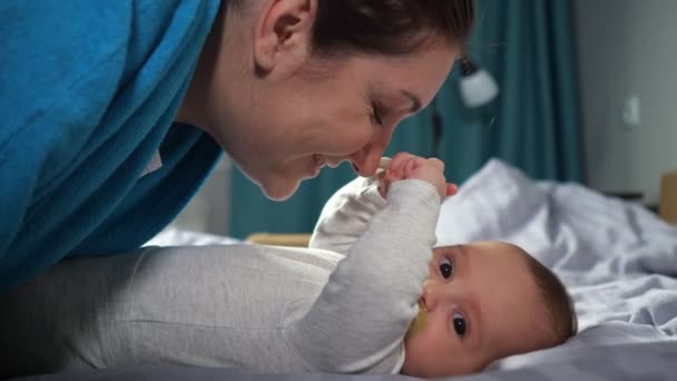 Ung mor böjer kyssar händer baby son ler brett — Stockvideo
