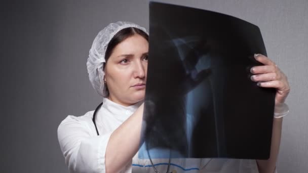 Lady ορθοπεδικός κοιτάζει ακτινογραφία εικόνα στο γραφείο κλινική — Αρχείο Βίντεο