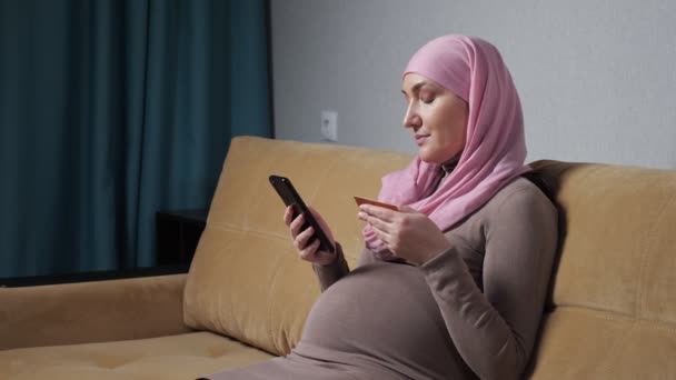 Mujer embarazada en hijab comprueba el número y hace una llamada telefónica — Vídeo de stock