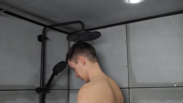 Genç adam duş alıyor evde soğuk suyun altında saç yıkıyor. — Stok video