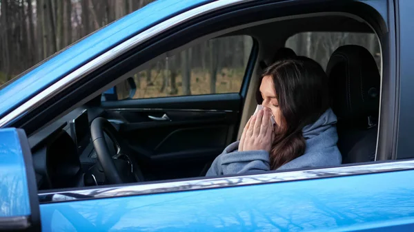 女は咳をして鼻を吹く紙ナプキンで車の中で座って — ストック写真