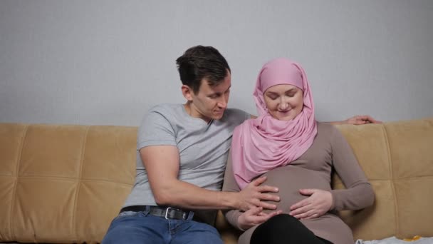 Müslüman anne ve baba gülümseyen hamile karnını okşarlar — Stok video