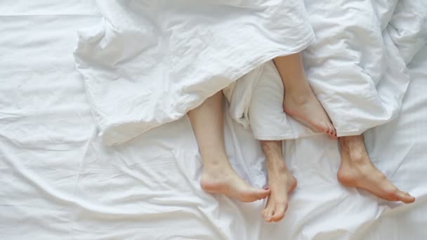 Pareja acaricia unos a otros acostados en la cama en sábanas blancas — Vídeo de stock