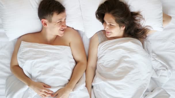 Casal jovem se comunica depois de acordar deitado na cama — Vídeo de Stock