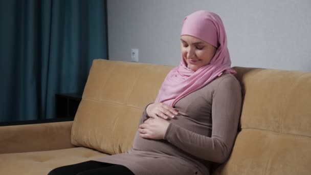 Muslim woman caresses pregnant belly and smiles happily — Stockvideo