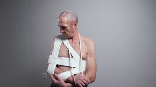 Homme âgé avec bandage examine épaule cassée au mur — Video