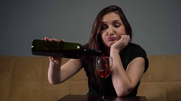女性はストレスと落ち込んで座っているガラスにワインを注ぐ — ストック写真