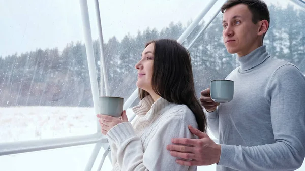 Hombre mascotas mujer en hombro disfrutando de la bebida en casa en invierno — Foto de Stock