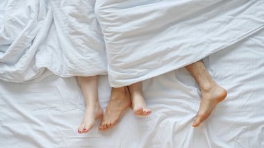 Genç çift, uyanıp yumuşak yatakta yattıktan sonra sevişiyor.