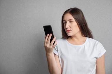Gözleri iyi görmeyen bir kadın telefon ekranına yakından bakar.