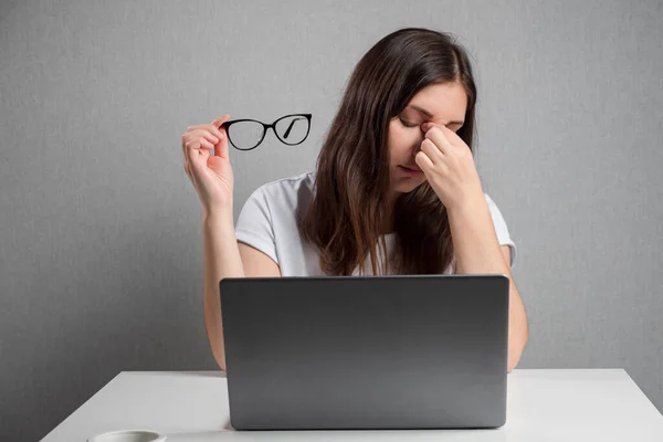 Müde Frau nimmt Brille am Laptop-Bildschirm ab — Stockfoto