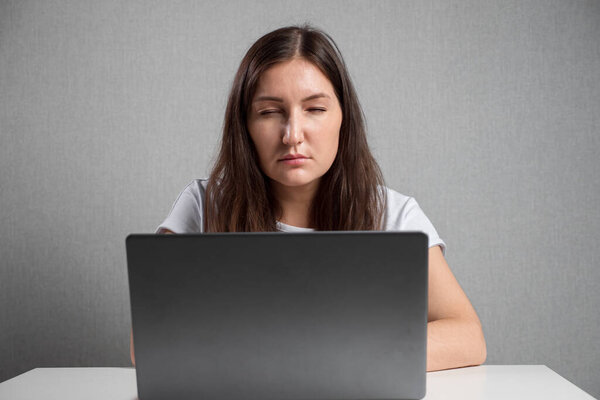 Woman with poor eyesight looks at laptop screen squinting