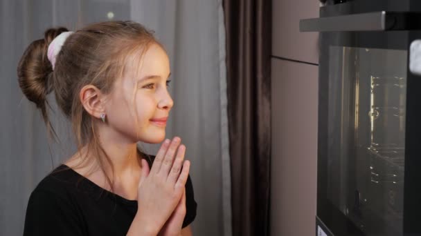 Tiener meisje wacht op voedsel bereiden in kachel thuis — Stockvideo
