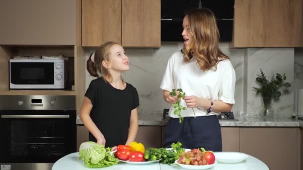 Anya ad tini lánya megkóstolni petrezselyem a konyhában — Stock videók