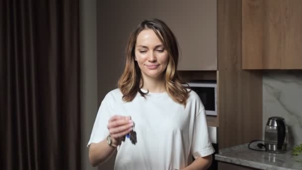 Happy woman shows key from apartment standing in kitchen — Stockvideo