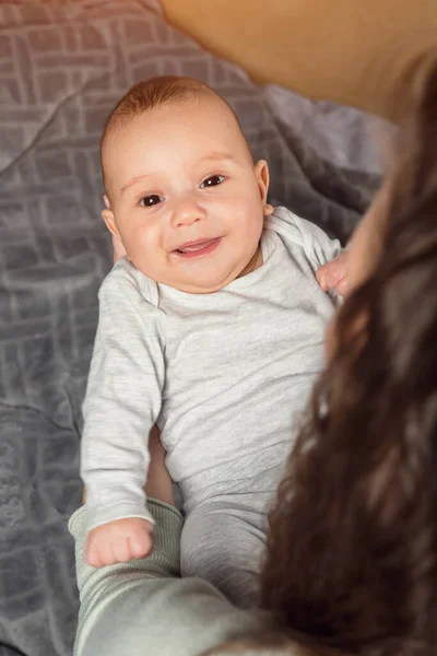 Adorable boy with a smiling face enjoys the caress of mom in arms — Zdjęcie stockowe