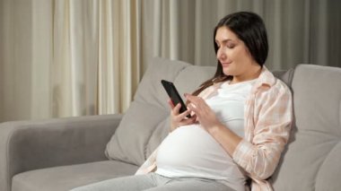 Pregnant woman scrolls through social media via smartphone