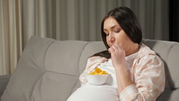 Femme enceinte aime manger de la malbouffe assis sur le canapé — Video