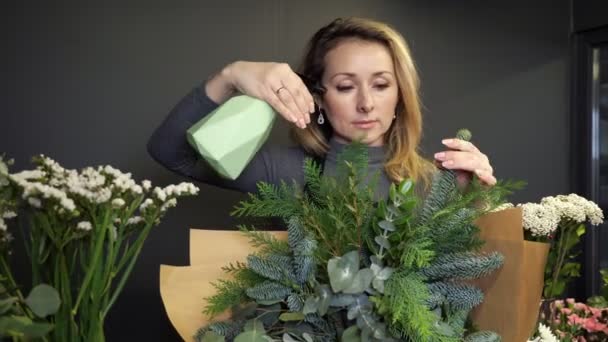 Blonde woman florist splashes water on fir tree bouquet — Vídeos de Stock