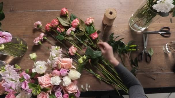 Bloemist vrouw componeert bruiloft boeket met kleurrijke rozen — Stockvideo