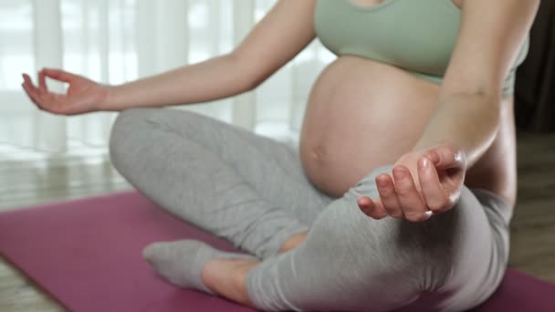 Woman with pregnant belly meditates sitting in lotus pose — Stock Video