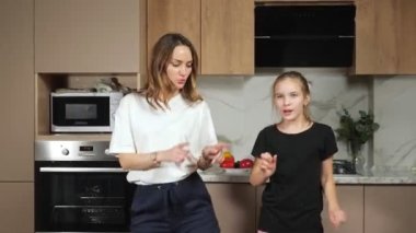 Anne ve genç kız mutfakta dans ediyorlar.