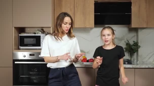 Mãe e adolescente filha dança na cozinha premissa em casa — Vídeo de Stock