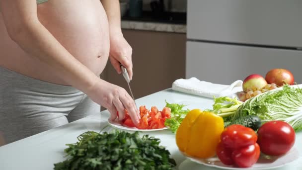 Woman cuts tomatoes on plate at table with vegetables — Αρχείο Βίντεο