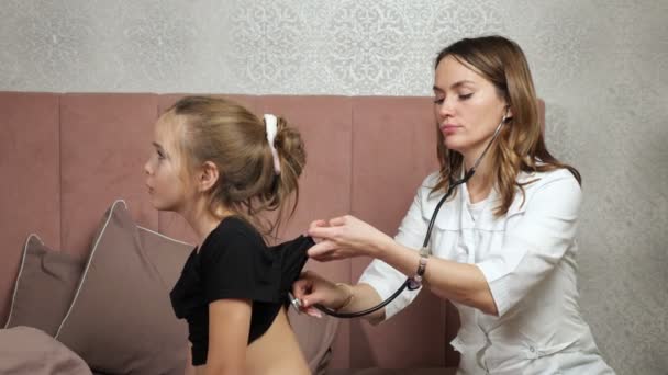 Lekarz słucha płuc chorej nastolatki ze stetoskopem — Wideo stockowe