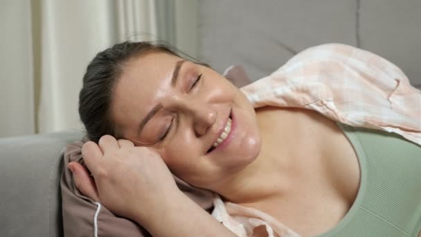Pregnant woman lies on sofa cushion strokes belly smiling — Stok video