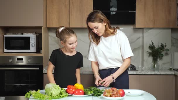 Moeder toont dochter snijden komkommer proces in keuken — Stockvideo