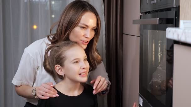 Mamma förklarar tonårsdotter matlagning process i spis — Stockvideo