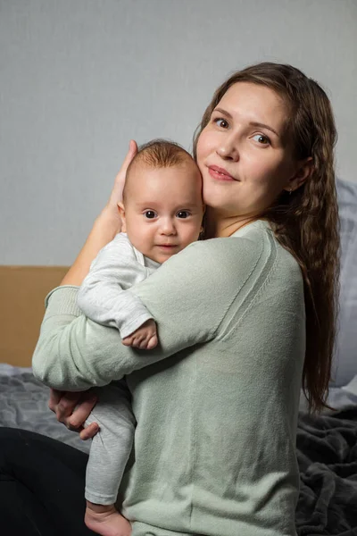 Maman aimante portant son nouveau-né à la maison. Portrait lumineux de maman heureuse tenant bébé sur les mains — Photo
