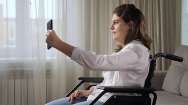 Tekerlekli sandalyedeki engelli kadın evdeki video konuşmasında konuşuyor